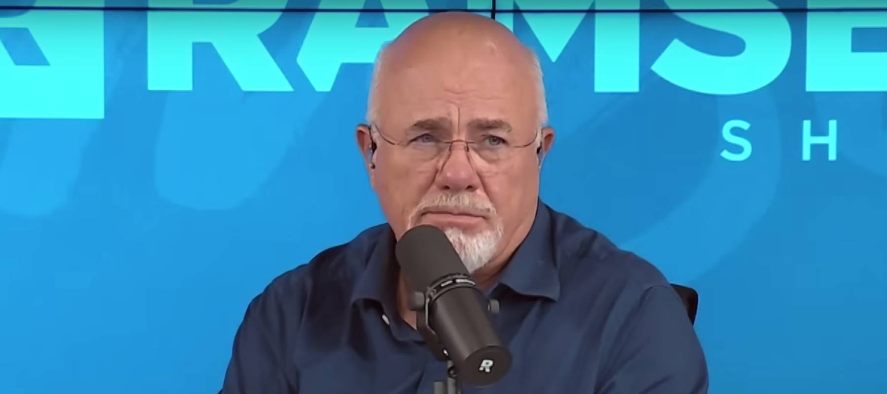 Dave Ramsey speaks into the microphone making a sassy face while on set of his radio show.