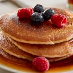 A person eating a stack of pancakes.