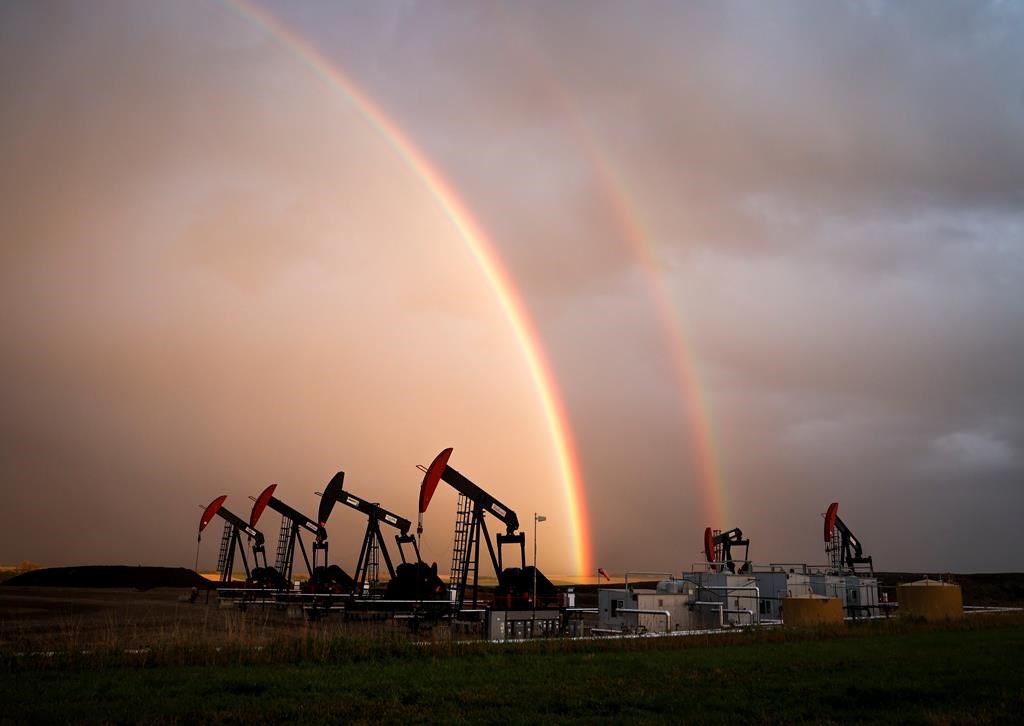 A rainbow appears to come down on pumpjacks drawing out oil and gas from wells near Calgary, Alta., Monday, Sept. 18, 2023. 