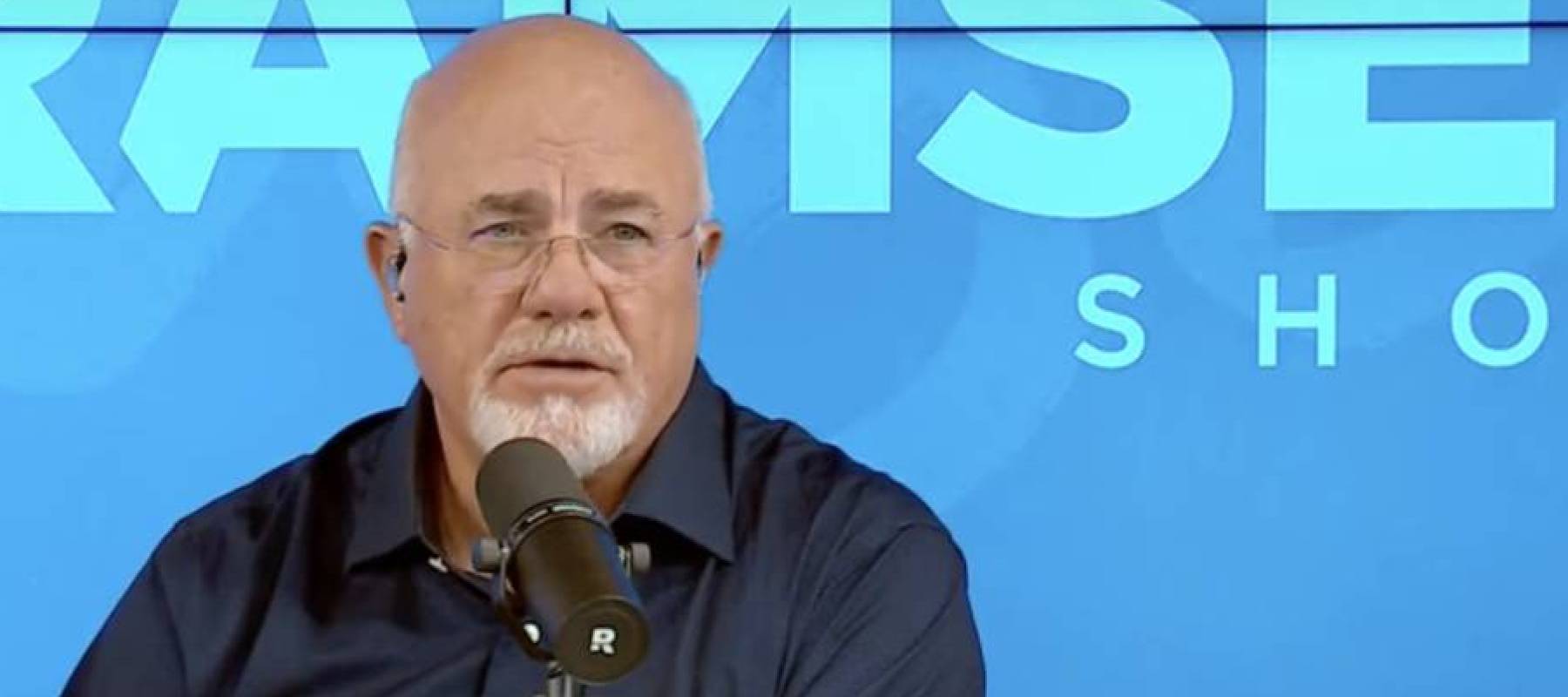 Dave Ramsey speaks into a microphone on the set of his radio show.