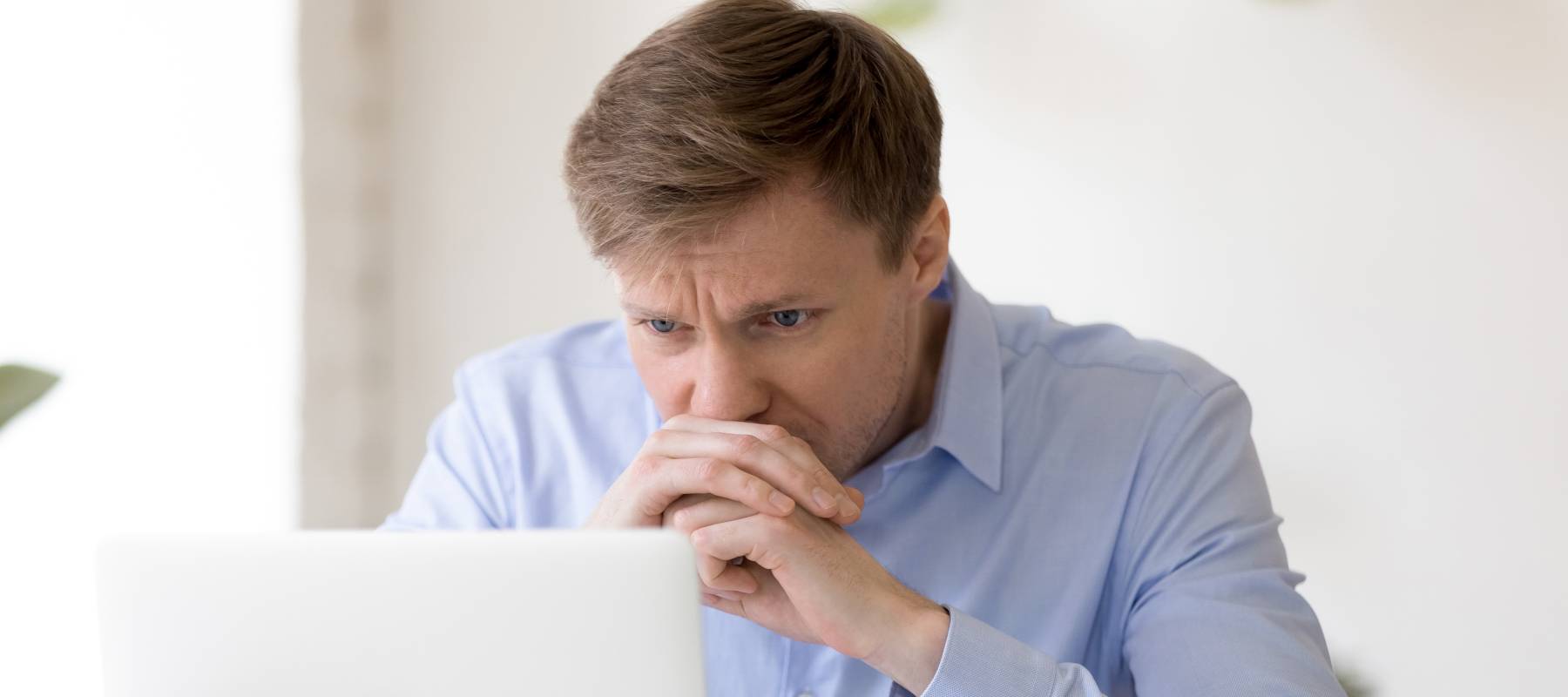 Focused puzzled businessman looking at laptop screen