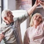An older couple dances in the kitchen.