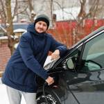Young man charging his electric car in winter gear.