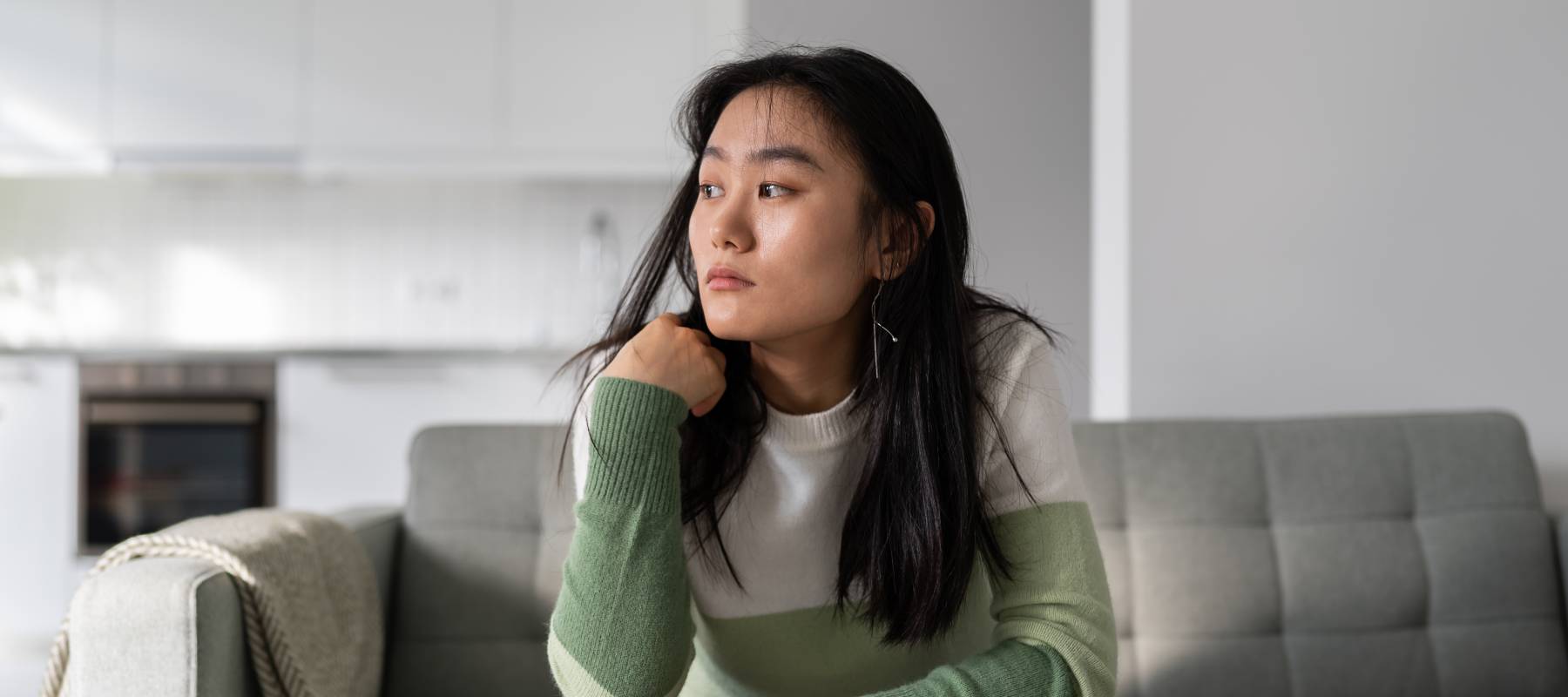 A woman sits stressed in her living room.