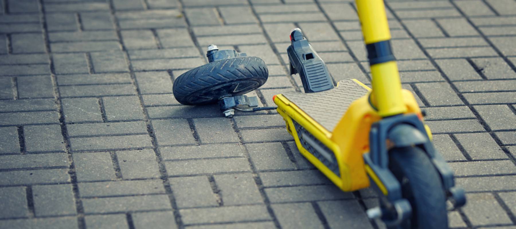 a broken yellow electric scooter on the pavement