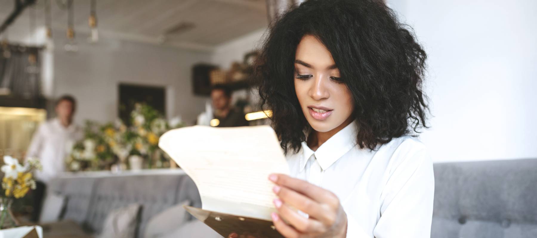 A woman looks at a menu in a restaurant.