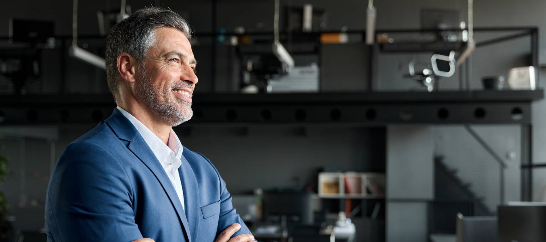 A businessman standing and smiling in an offie space.