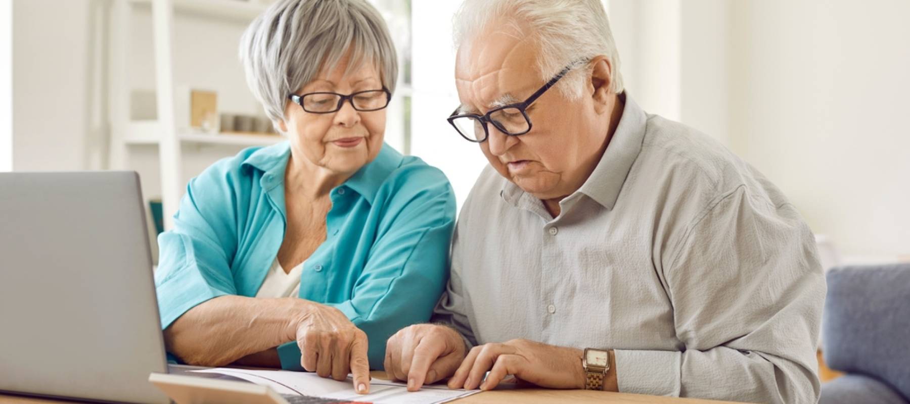 older Asian couple looking concerned at financial documents at kitchen table
