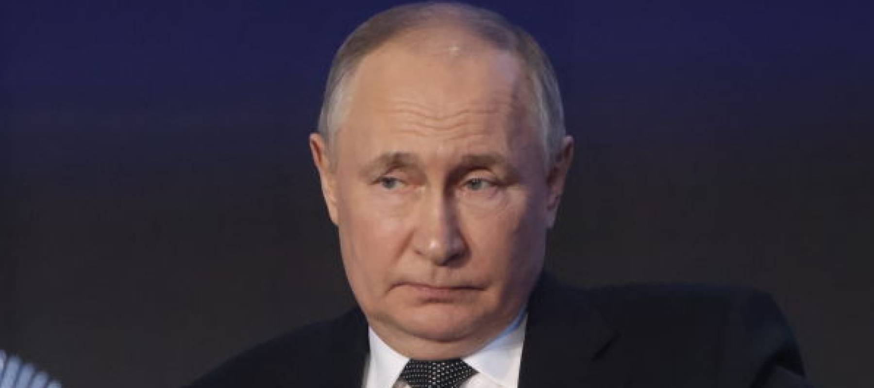 Russian President Vladimir Putin seen on stage, looking off to the side of the stage.