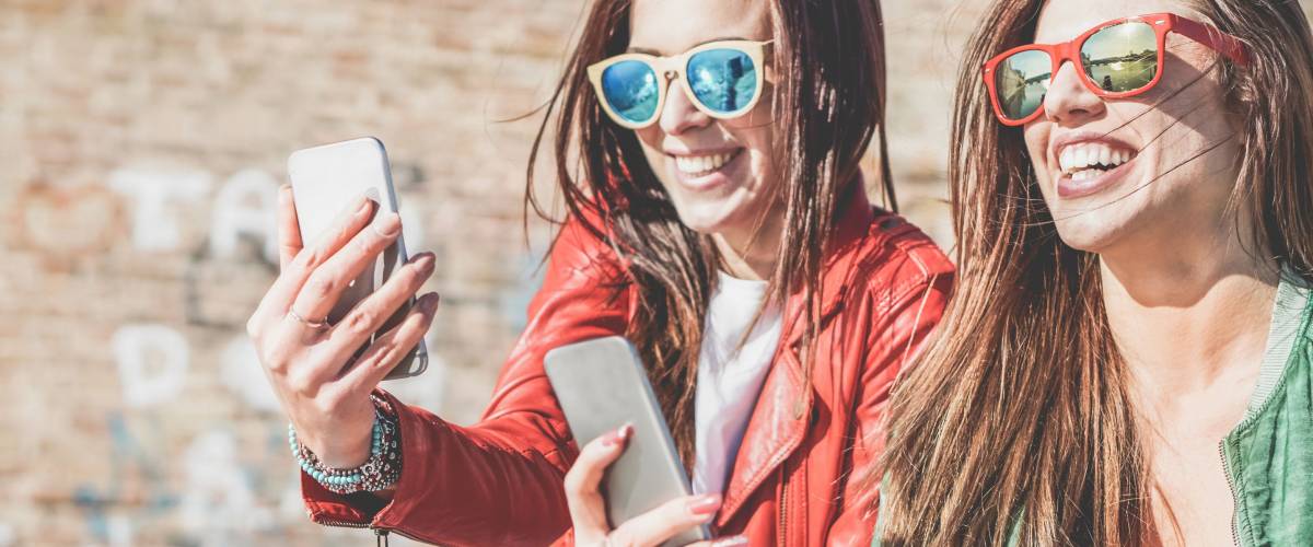 Having Fun While You Re Young Is A Bad Excuse To Not Save Money - happy fashion friends watching videos on smartphone girlfriends having fun social technology trends outdoors