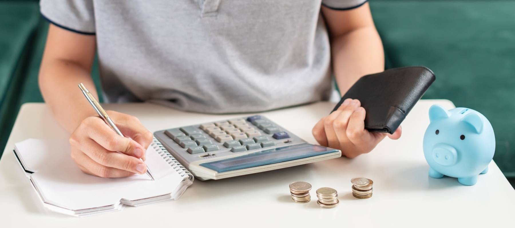 Kid teen boy counting money and taking notes, saving money in a piggy bank.