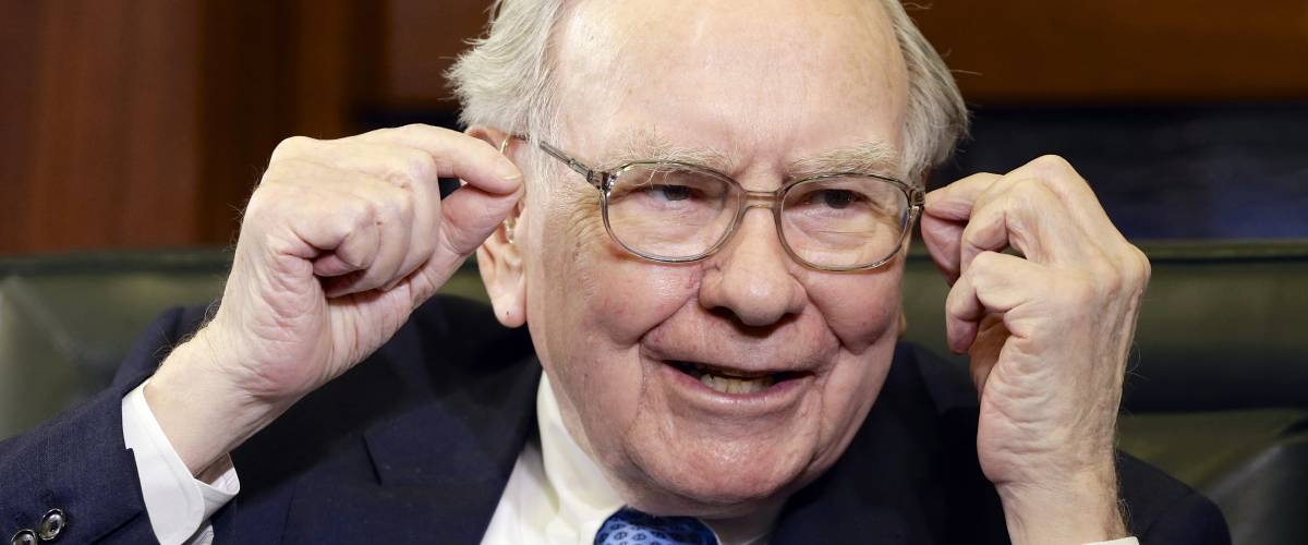 Warren Buffett smiling and gesturing with both hands