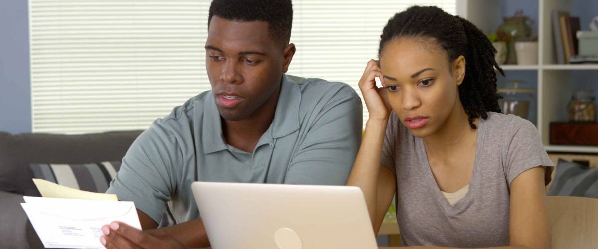 Frustrated young Black couple going over bills and finances online
