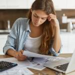Portrait of worried woman feeling stressed while working through finances in kitchen late at night, thinking how to pay off credit card debt