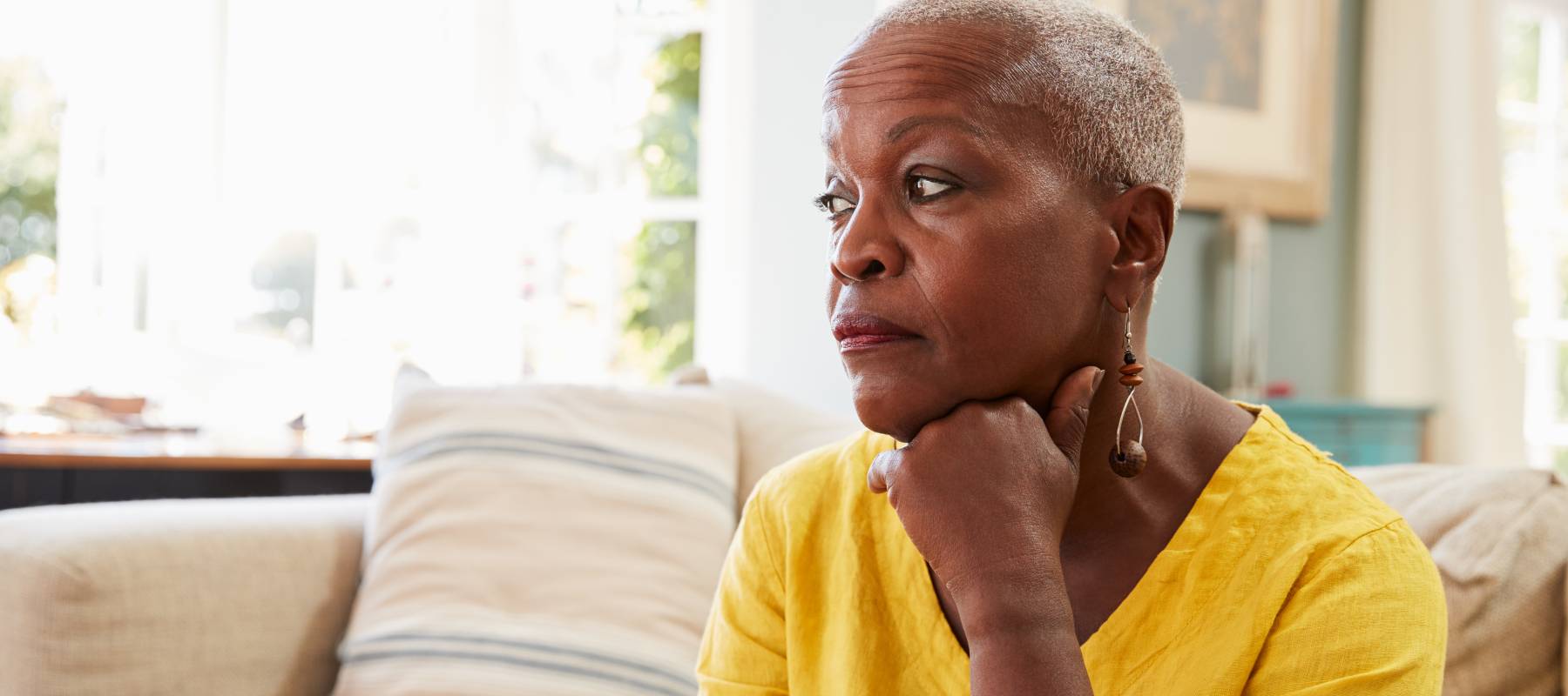 senior Black woman looking concerned sitting on a couch