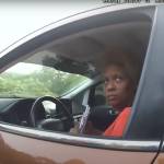 Woman seen from inside car, looking out with window rolled down.