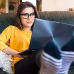 Woman sitting on the couch using a laptop.