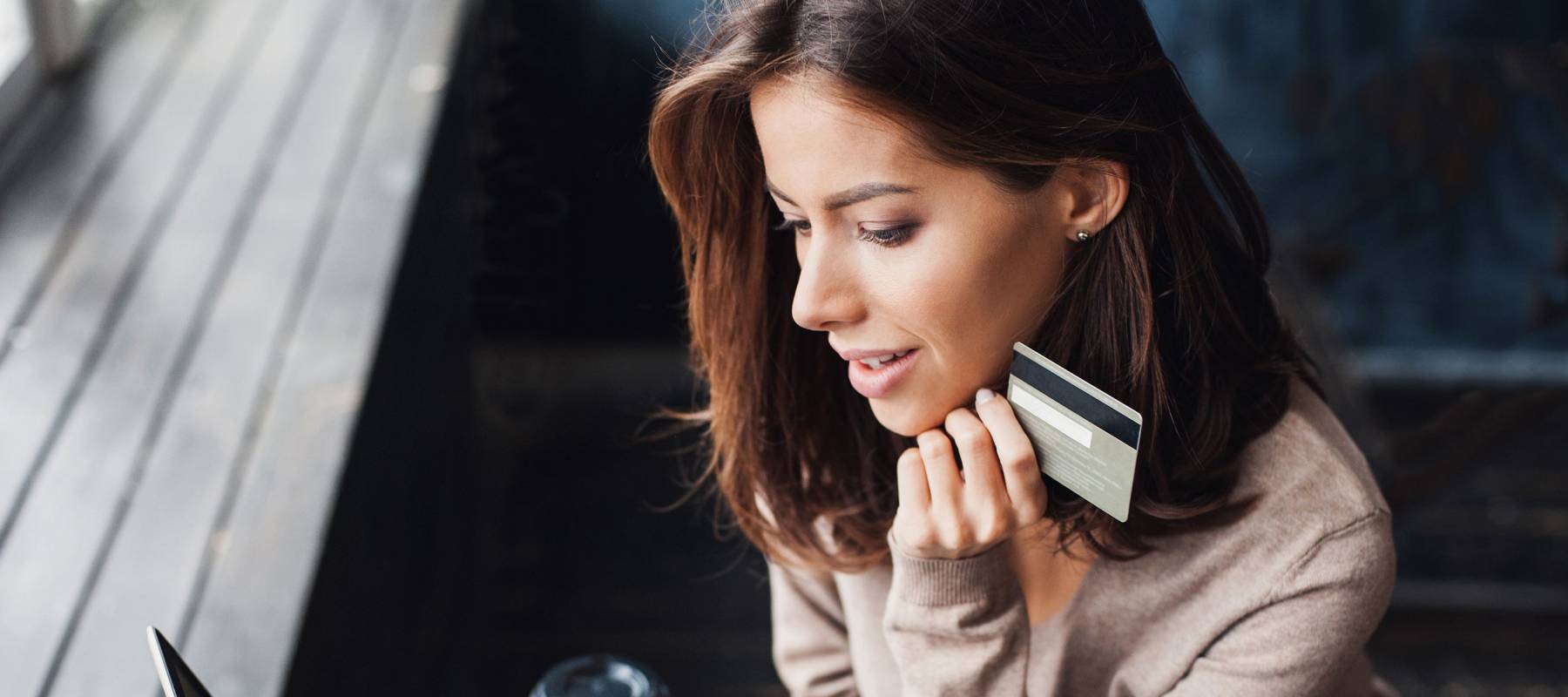Young woman holding credit card and using laptop computer.