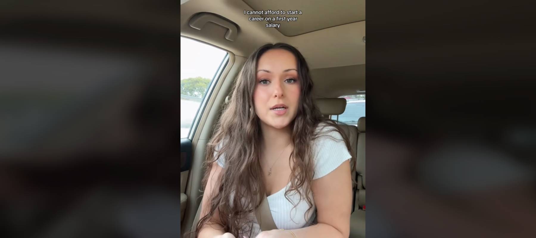 Woman sitting in front seat of car, talking directly to the camera with stern look on her face.