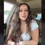 Woman sitting in front seat of car, talking directly to the camera with stern look on her face.