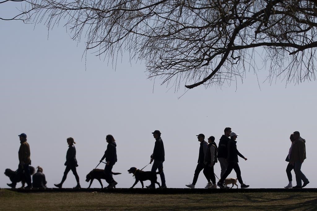 Statistics Canada says the country posted its highest annual population growth rate in more than six decades last year. People walk along the boardwalk in Toronto&#039;s east end on Sunday, April 
