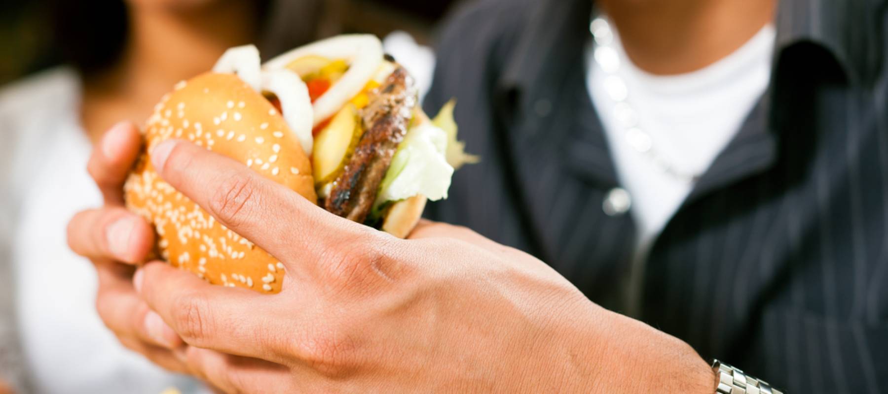man (African American) in a fast food restaurant eating a hamburger with his girlfriend