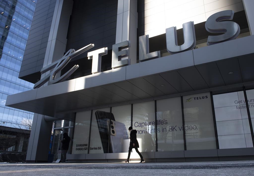 A woman walks in front of the Telus head office is shown in Toronto on Thursday, February 11, 2021. Shares of some of Canada&#039;s big telecommunications companies fell as BMO Capital Markets cut