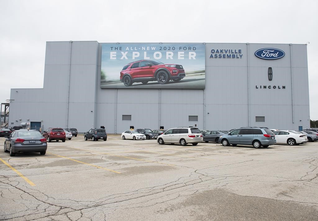 A parking lot with employees&#039; vehicles is shown at the Ford assembly plant in Oakville, Ont., on Thursday, March 19, 2020. Ford Motor Co. is delaying the start of electric vehicle production 