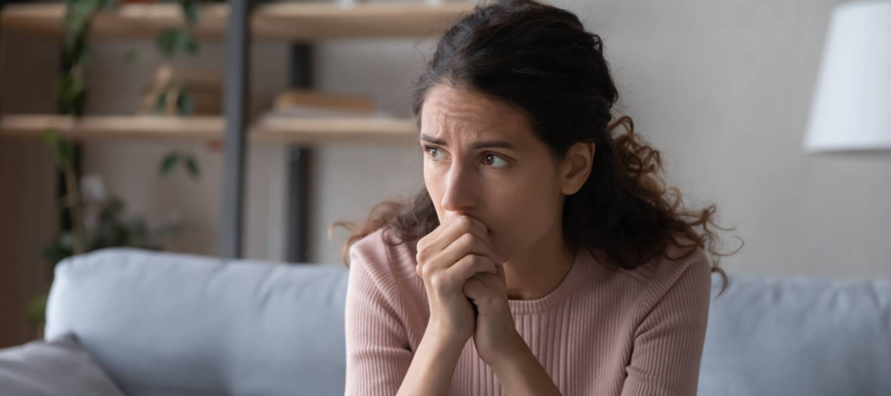 Nervous young woman sitting on sofa