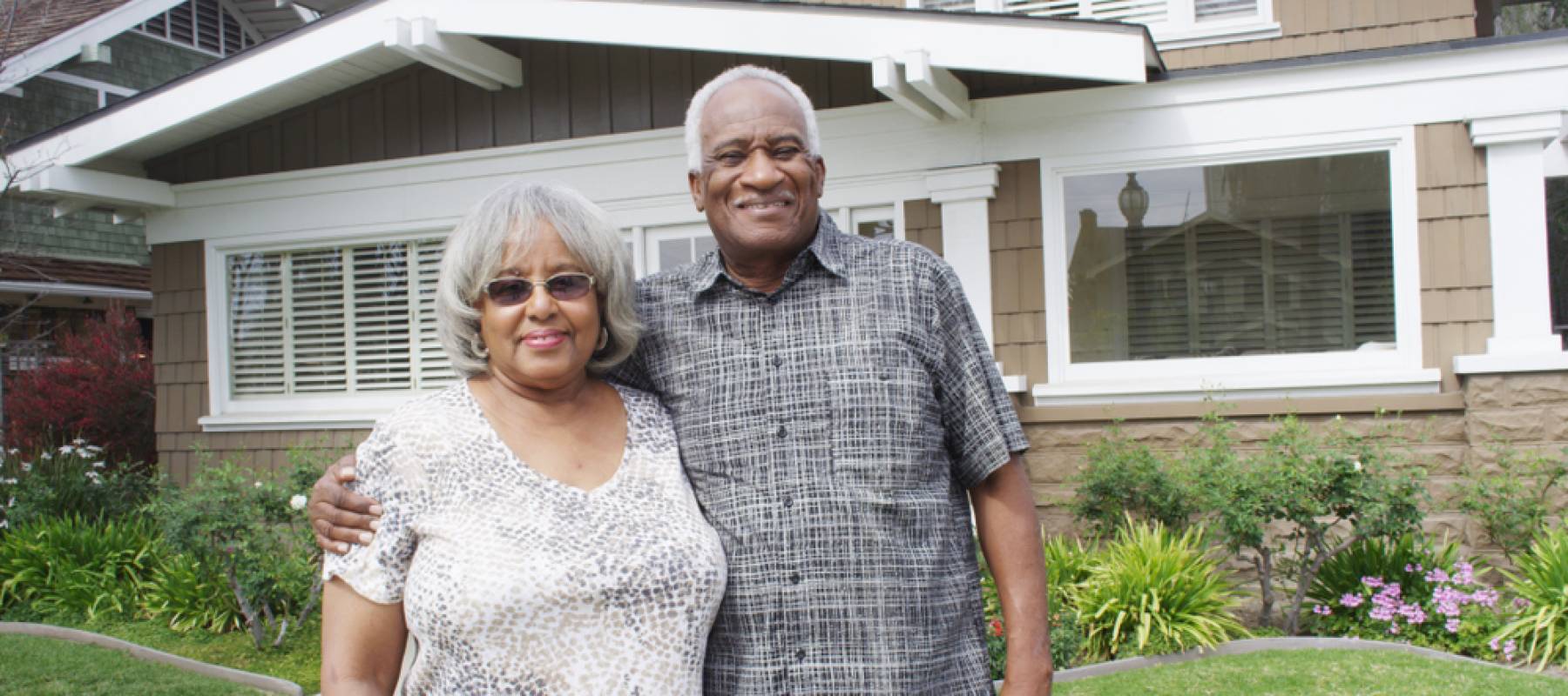 Happy elderly couple standing on front yard