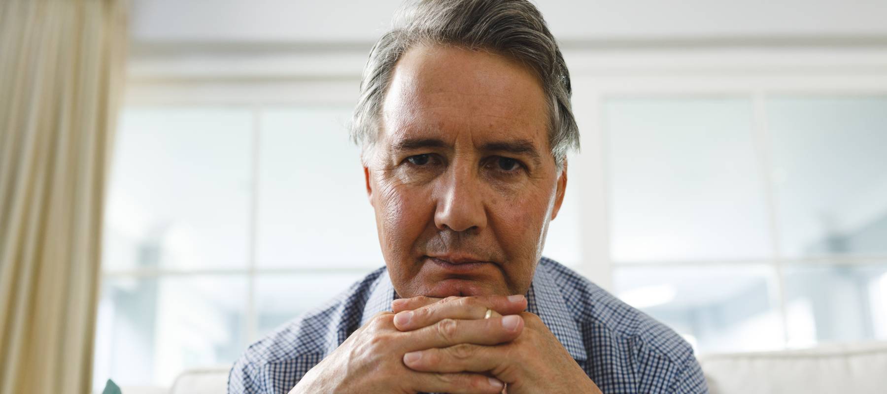 Well-groomed older man looks directly at the camera, stressed.