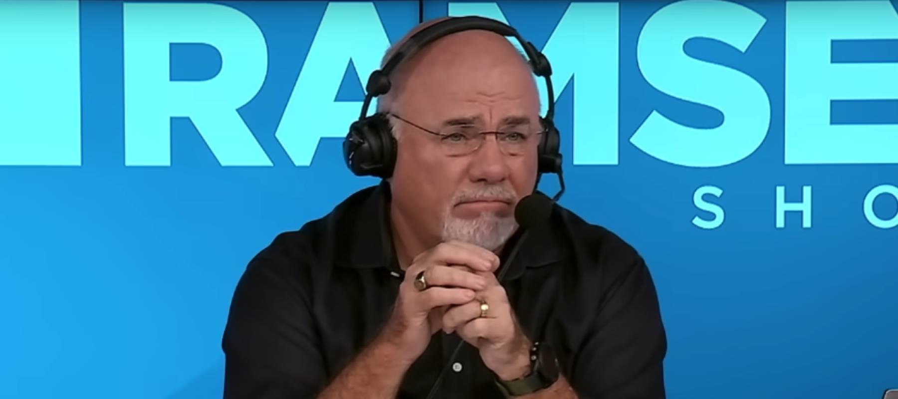 Dave Ramsey clasps his hands together while talking on set of his radio show.