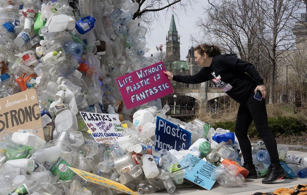 Activist Dianne Peterson places a sign on a public art installation outside a United Nations conference on plastics, Tuesday, April 23, 2024 in Ottawa. 