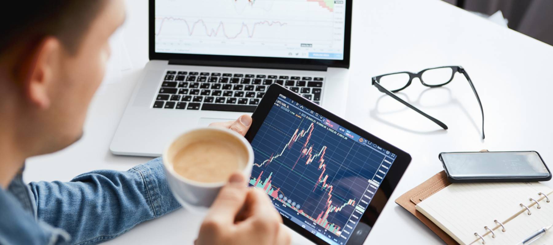 Young man watching stocks on a laptop and tablet
