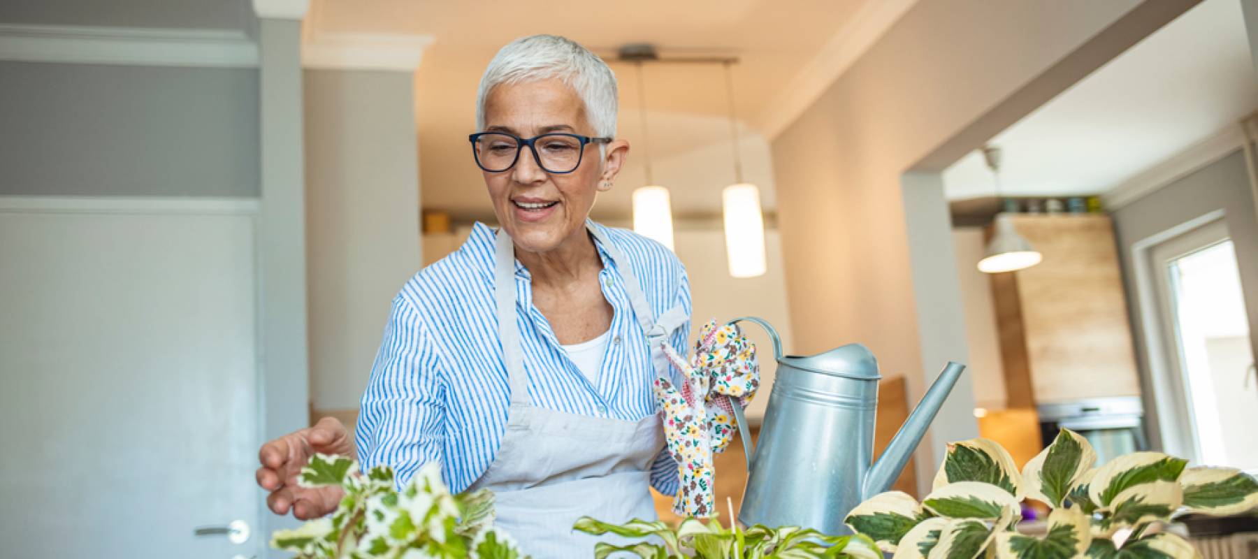Senior woman with green plants and flowers at home