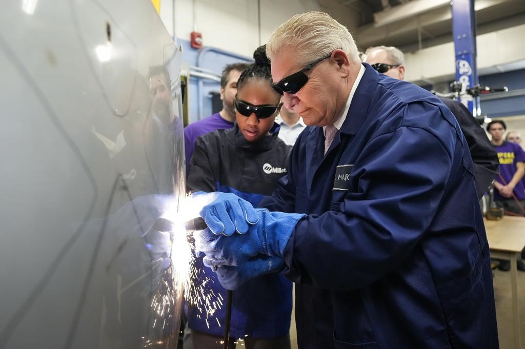 Ontario Premier Doug Ford, right, gets help from grade 11 student Shannon Williams, 16, as they practise welding at St. Mary Catholic Secondary School in Pickering, Ont., on Wednesday, March 