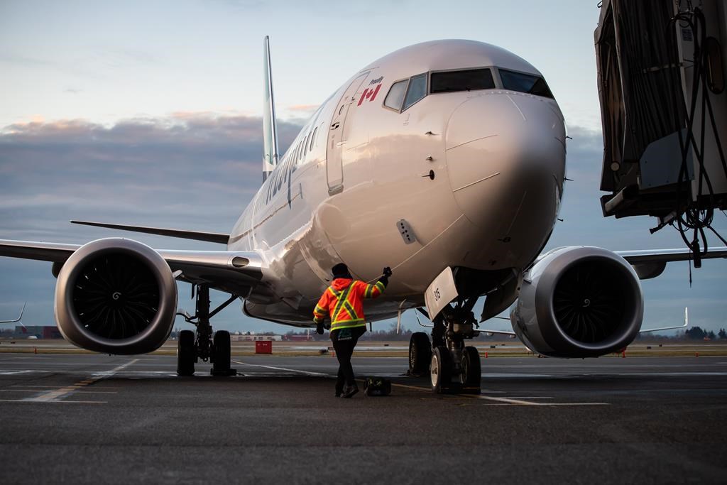 A ground worker approaches a WestJet Airlines Boeing 737 Max aircraft after it arrived at Vancouver International Airport in Richmond, B.C., on Thursday, January 21, 2021. WestJet has issued 