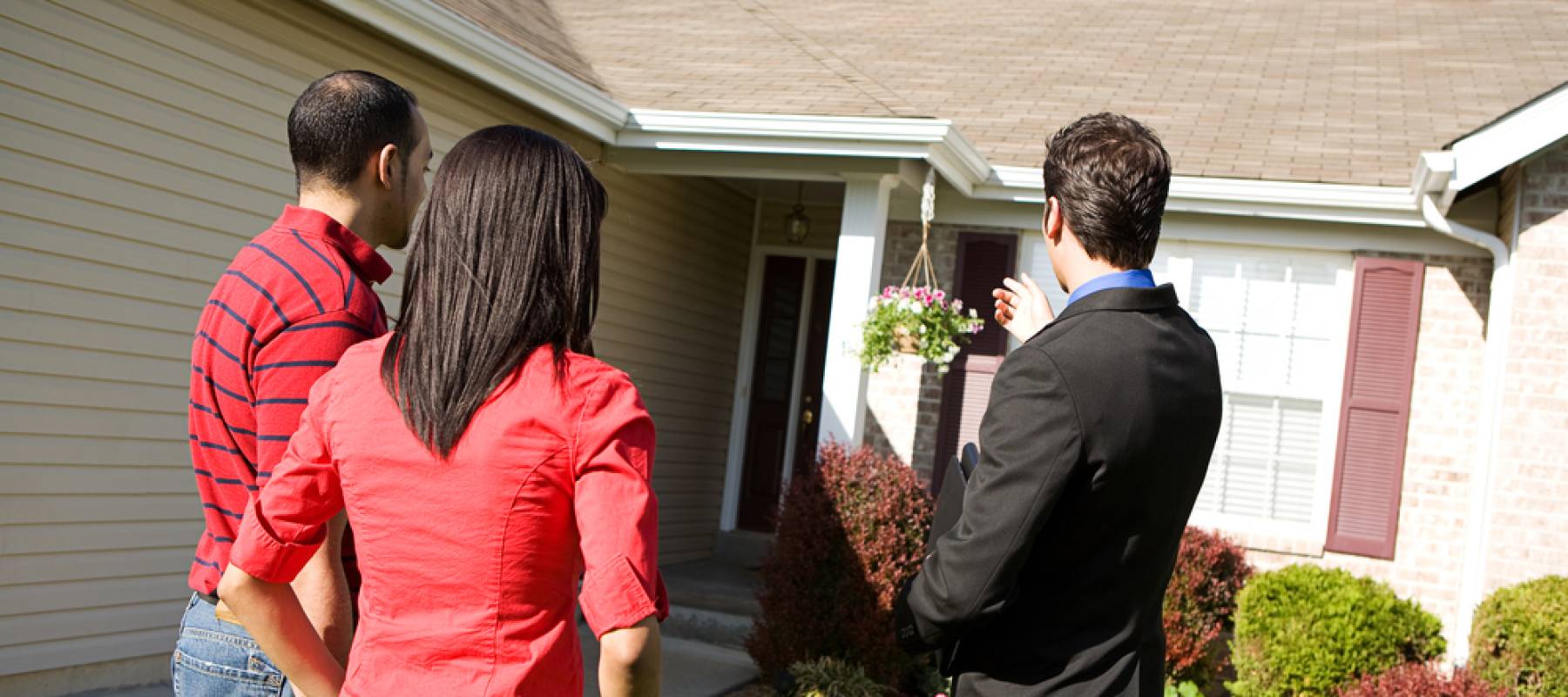 Real estate agent shows couple a home, seen from behind.