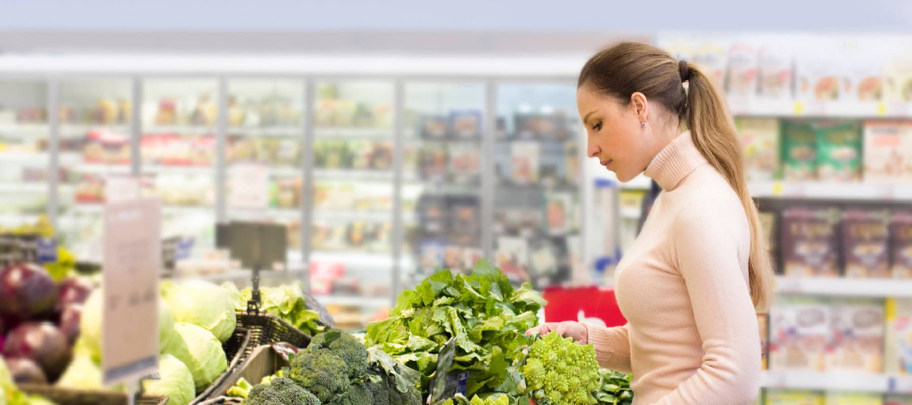 Caucasian woman looking at veggie stand in grocery store