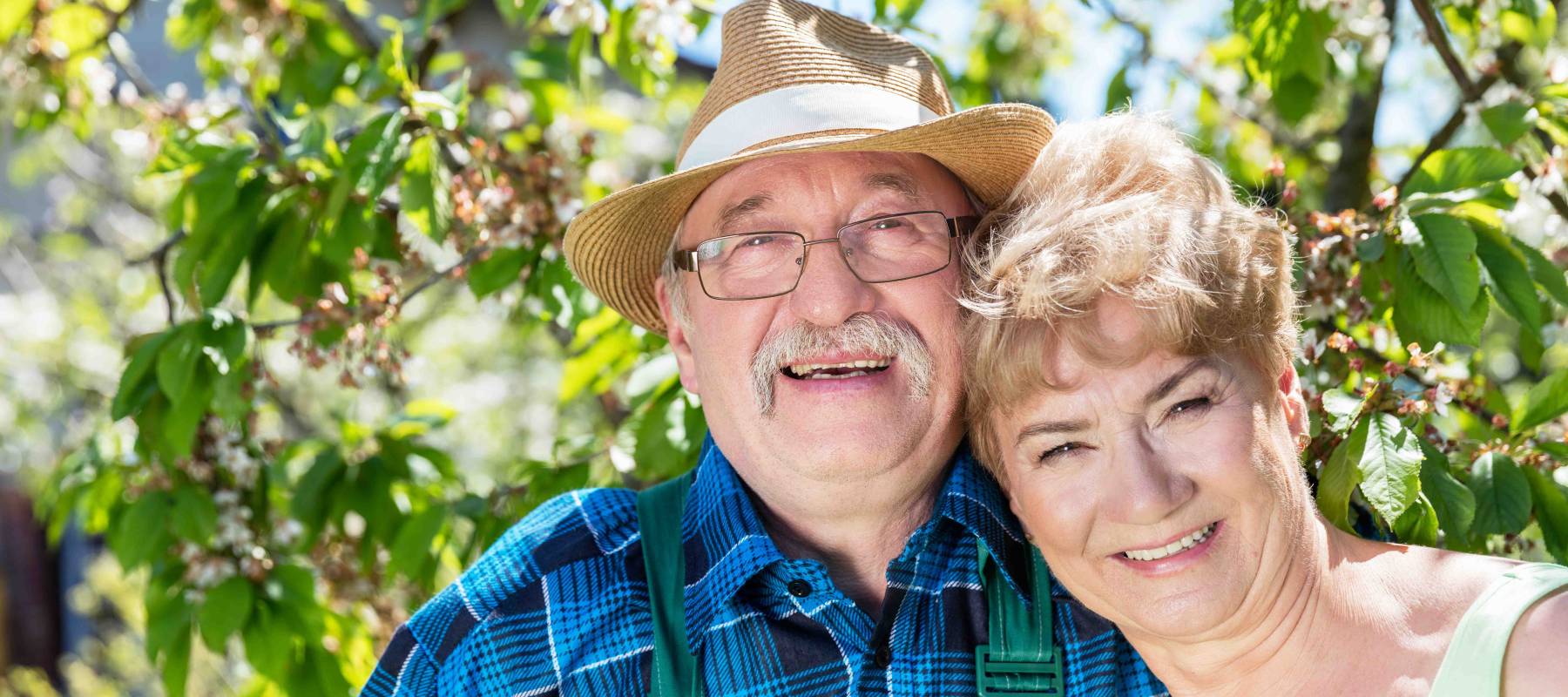 Mature, smiling couple embracing time together in the summer garden. Happy active seniors.