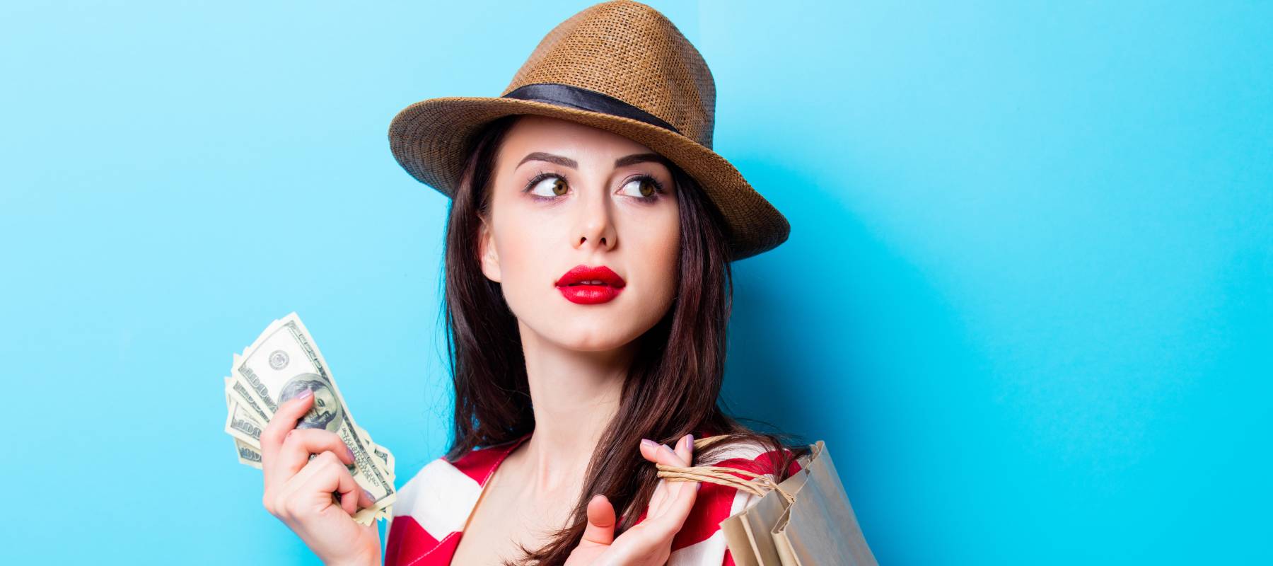 A young woman with cash and shopping bags.