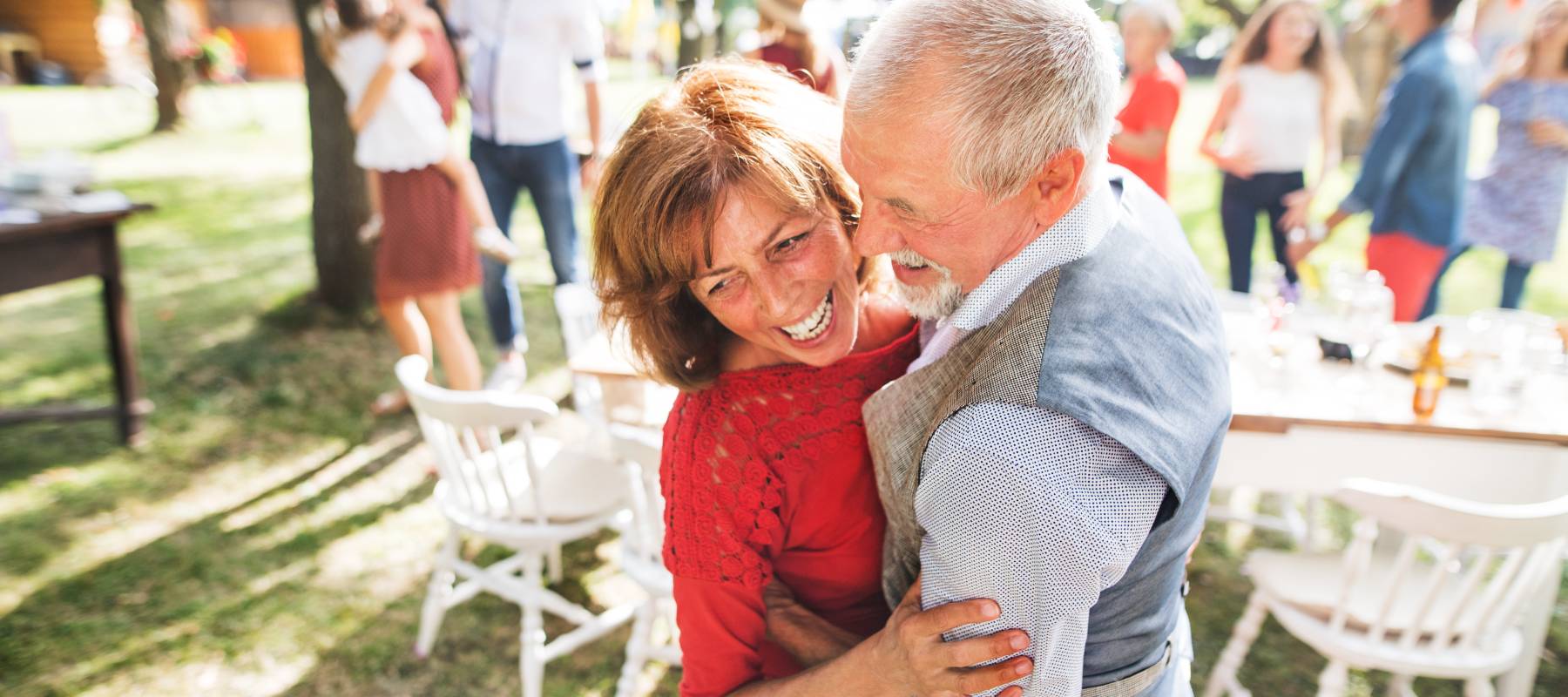 An older couple dance at a garden party.