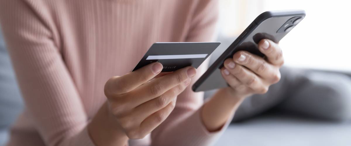 Woman holding her phone and credit card to pay for something