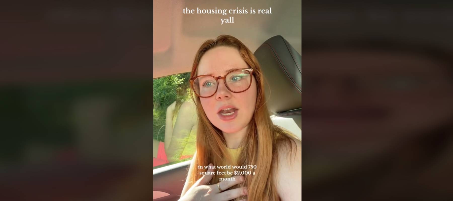 Woman wearing glasses sitting in a car talking directly to camera, gesturing.
