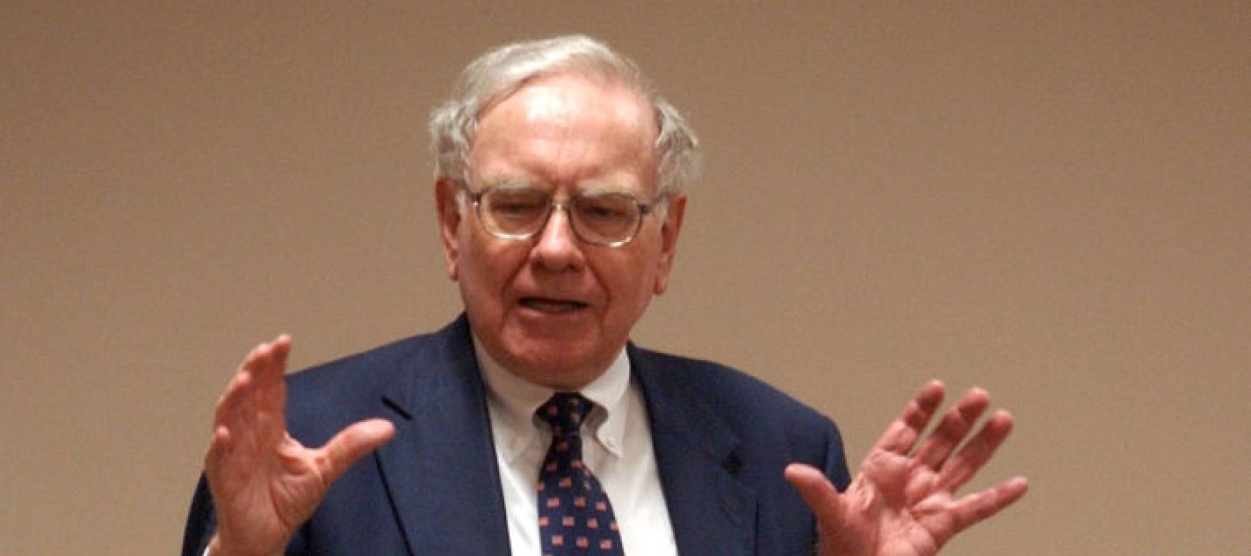 Warren Buffett speaking with his hands held up.
