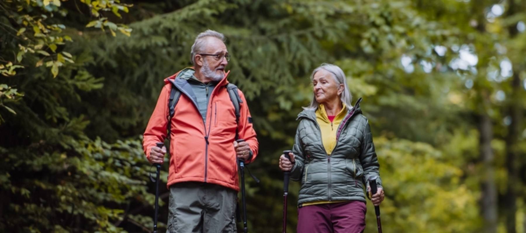 Happy senior couple hiking in autumn forest.