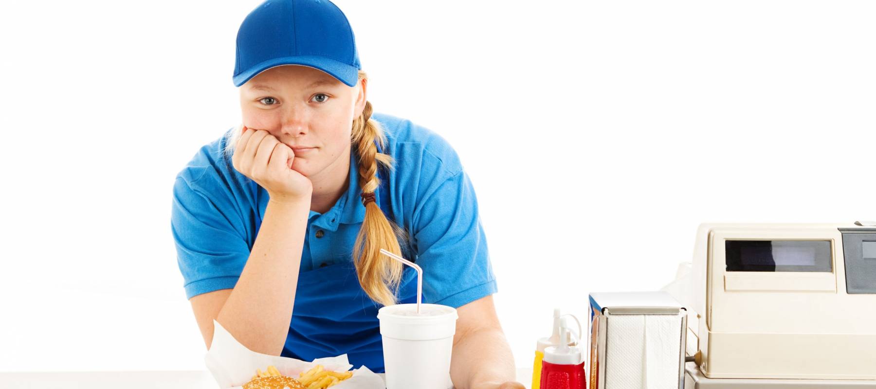Teenage worker in a fast food restaurant bored and leaning on the counter.  White background.