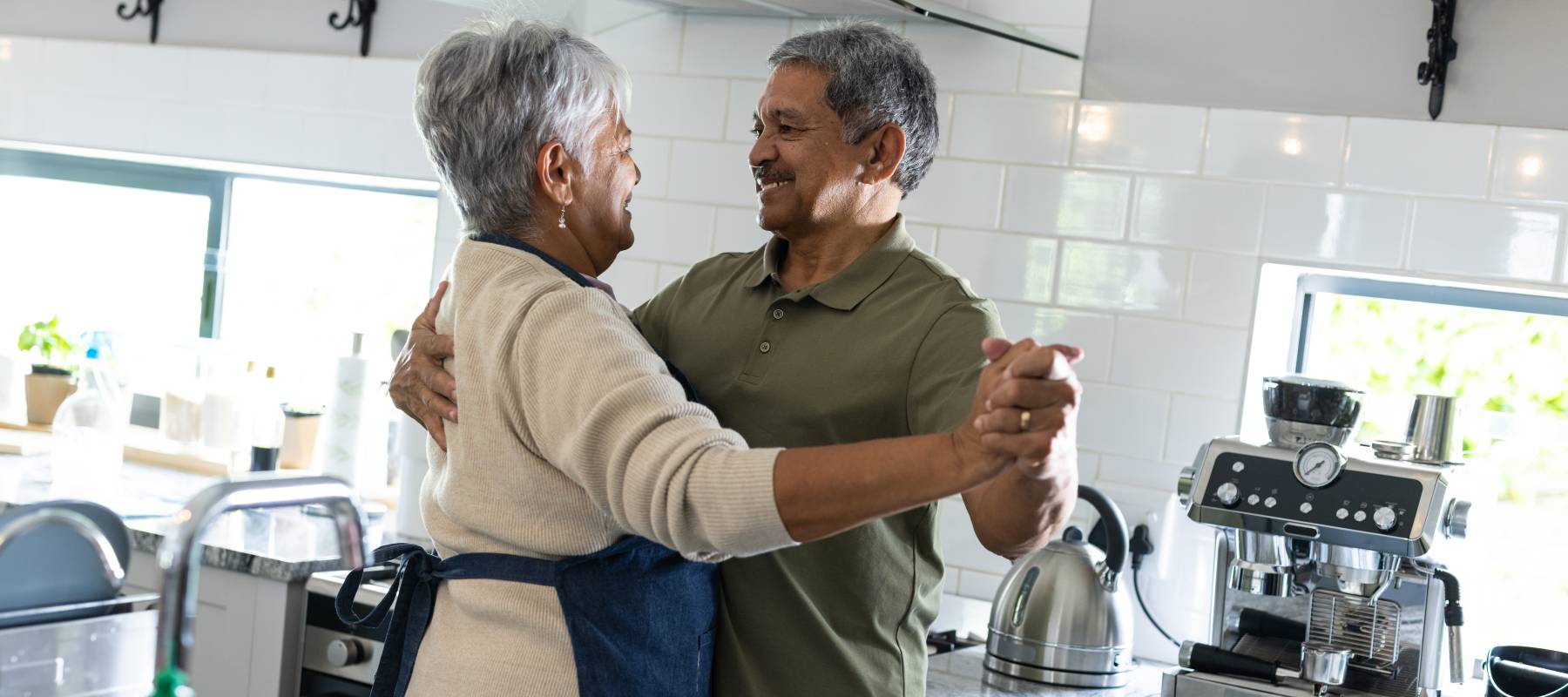 An older couple dancing in their home kitchen.