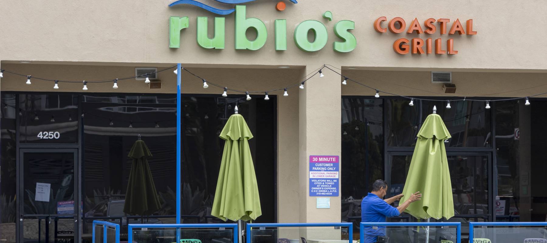 A worker closes the umbrellas at a Rubio's Costal Grill in Los Angeles, June 3, 2024.