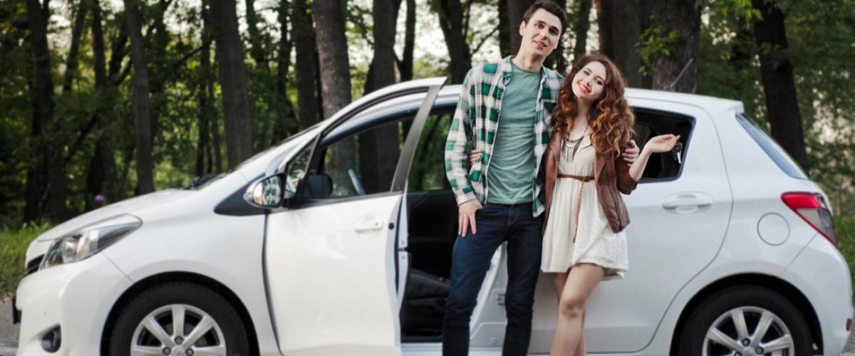 Young couple standing next to their car